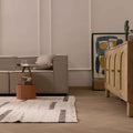 Handwoven white and brown wool-blend flatweave rug with a modern geometric pattern in a cozy living room.