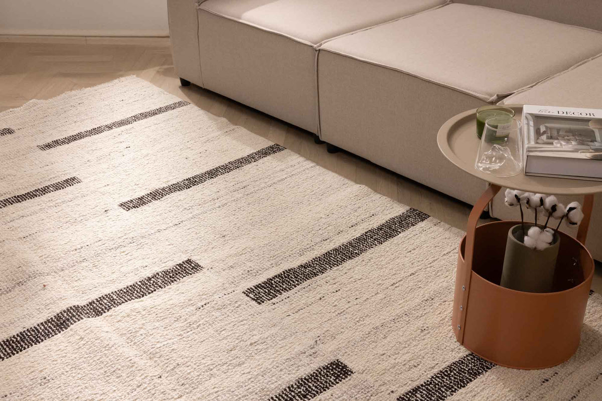 Handwoven white and brown wool-blend flatweave rug with a modern striped pattern in a living room setting.