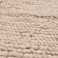 Close-up of a soft, apricot-colored shaggy wool rug featuring a thick, handwoven high-pile texture.