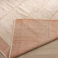 Handwoven apricot shaggy wool rug with a thick pile, grid pattern, and folded corner showing the durable cotton backing.