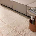 Apricot shaggy wool rug with a thick, textured pile and subtle grid pattern, placed in a cozy living room setting.