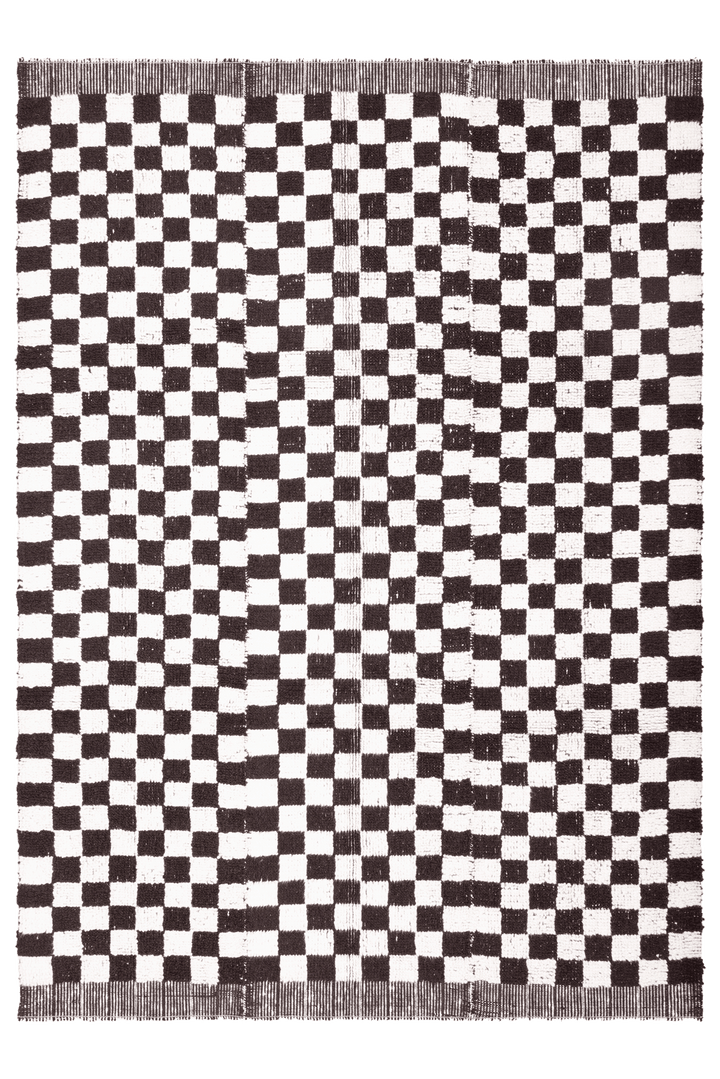 Handwoven black and white checkered shaggy wool rug with a thick, soft pile and durable cotton blend construction.