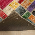 Handmade 5x8 ft patchwork Turkish rug with vibrant floral wool and cotton squares and a stitched dark fabric backing.