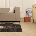 5x7 ft black distressed patchwork Turkish wool and cotton rug with eclectic patterns in a modern living room.