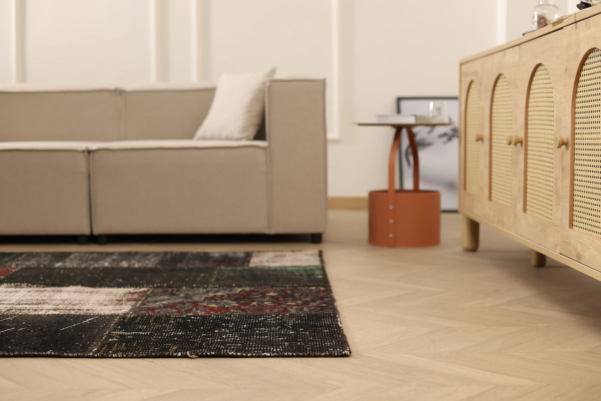 5x7 ft black distressed patchwork Turkish wool and cotton rug with eclectic patterns in a modern living room.
