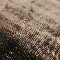 Close-up of a black and brown distressed patchwork wool and cotton vintage Turkish rug with textured weave.