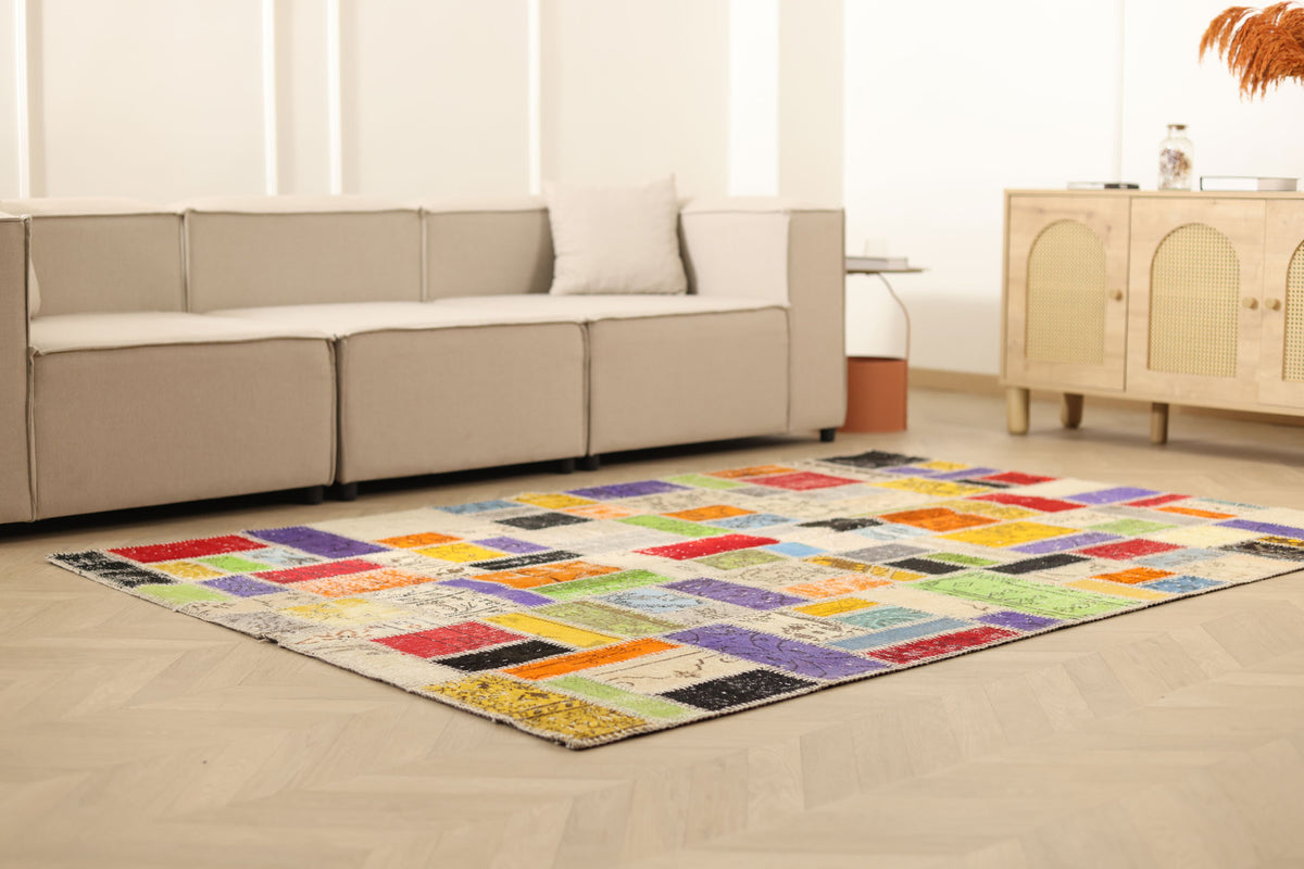 Handmade 5x8 ft vintage patchwork area rug featuring vibrant, multi-colored floral patterns in wool and cotton.