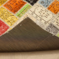 Handmade 5x8 ft vintage Turkish patchwork rug with vibrant floral wool and cotton squares and a dark protective backing.