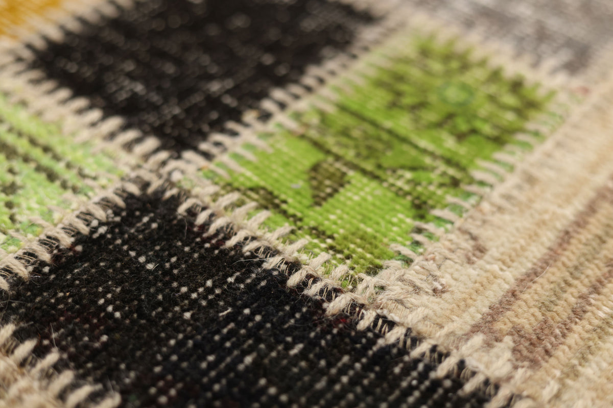 Close-up of a handmade Turkish patchwork rug featuring stitched wool and cotton squares in vibrant green, black, and neutral tones.