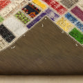 Handmade 5x8 ft vintage Turkish patchwork rug with vibrant multicolored floral wool and cotton squares and a fabric backing.