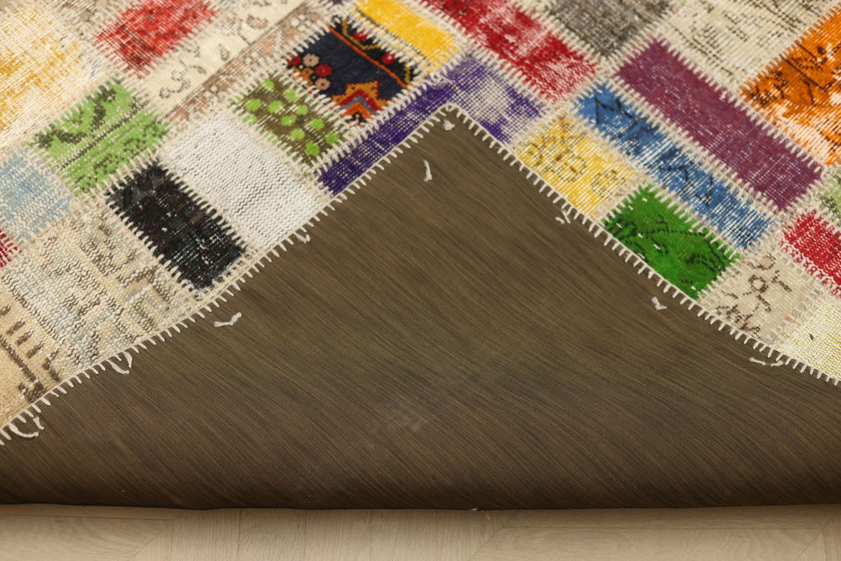 Handmade 5x8 ft vintage Turkish patchwork rug with vibrant multicolored floral wool and cotton squares and a fabric backing.