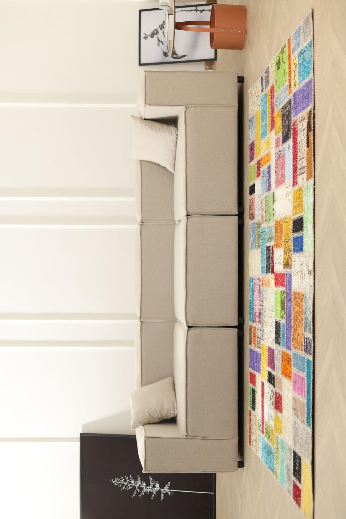 Handmade 5x7 ft vintage Turkish patchwork rug with vibrant geometric patterns in wool and cotton next to a beige sofa.