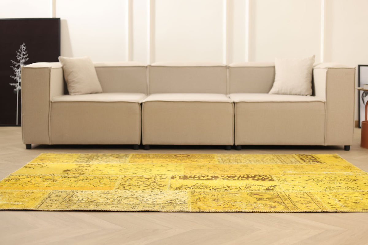 Yellow vintage Turkish patchwork area rug with overdyed patterns and bohemian style in a modern living room setting.