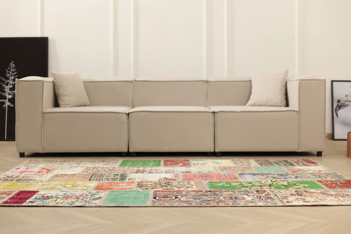 5x7 ft vintage Turkish patchwork area rug with vibrant floral patterns in wool and cotton, set before a beige sofa.