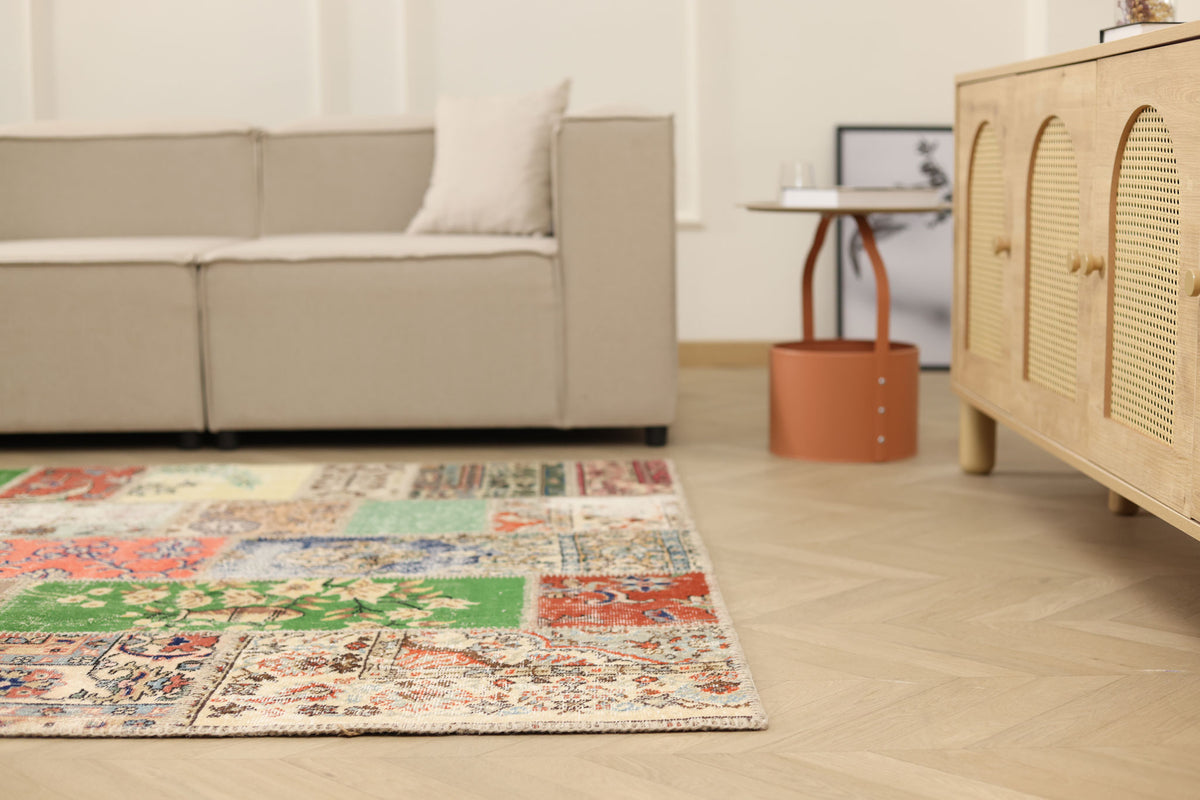 Handmade 5x7 patchwork Turkish rug with vibrant floral patterns in wool and cotton on a light wood floor.