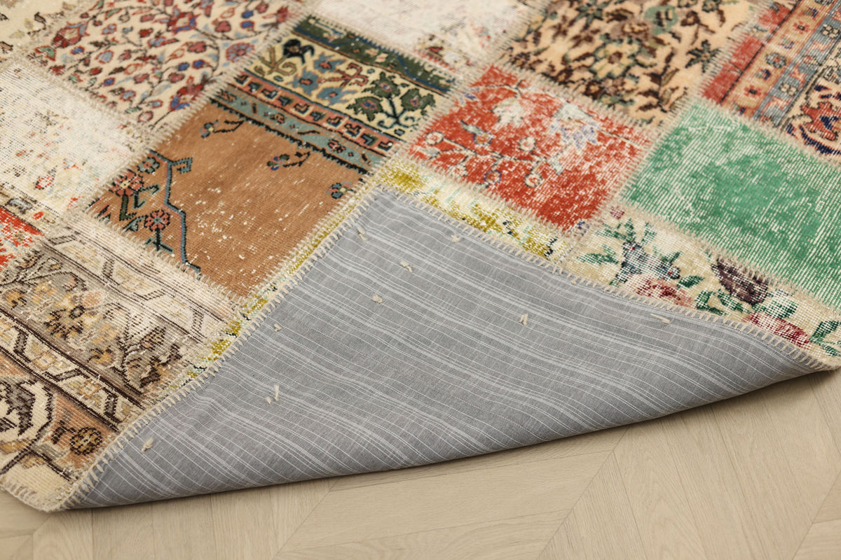 Handmade 5x7 ft patchwork Turkish area rug with vibrant floral patterns, wool and cotton blend, showing its grey fabric backing.