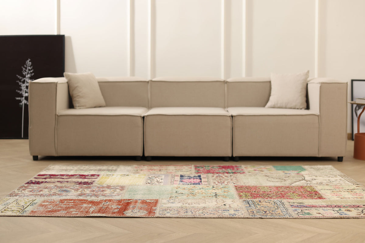 Handmade 5x7 ft patchwork Turkish area rug with vibrant floral patterns in wool and cotton, styled in a modern living room.