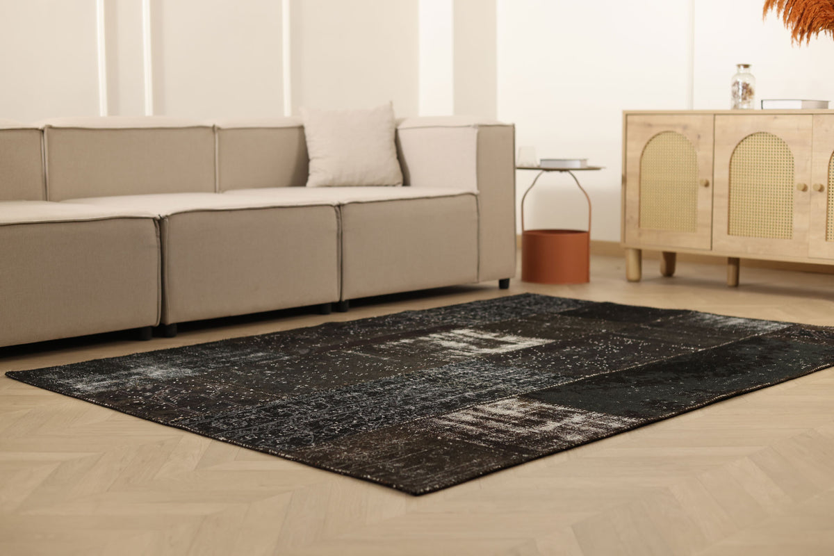 5x7 ft black distressed patchwork Turkish wool and cotton area rug in a modern bohemian living room.