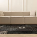 Handmade black patchwork wool and cotton area rug with distressed vintage patterns in a modern living room.