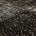 Handmade black patchwork Turkish area rug with distressed, overdyed wool and cotton textures.