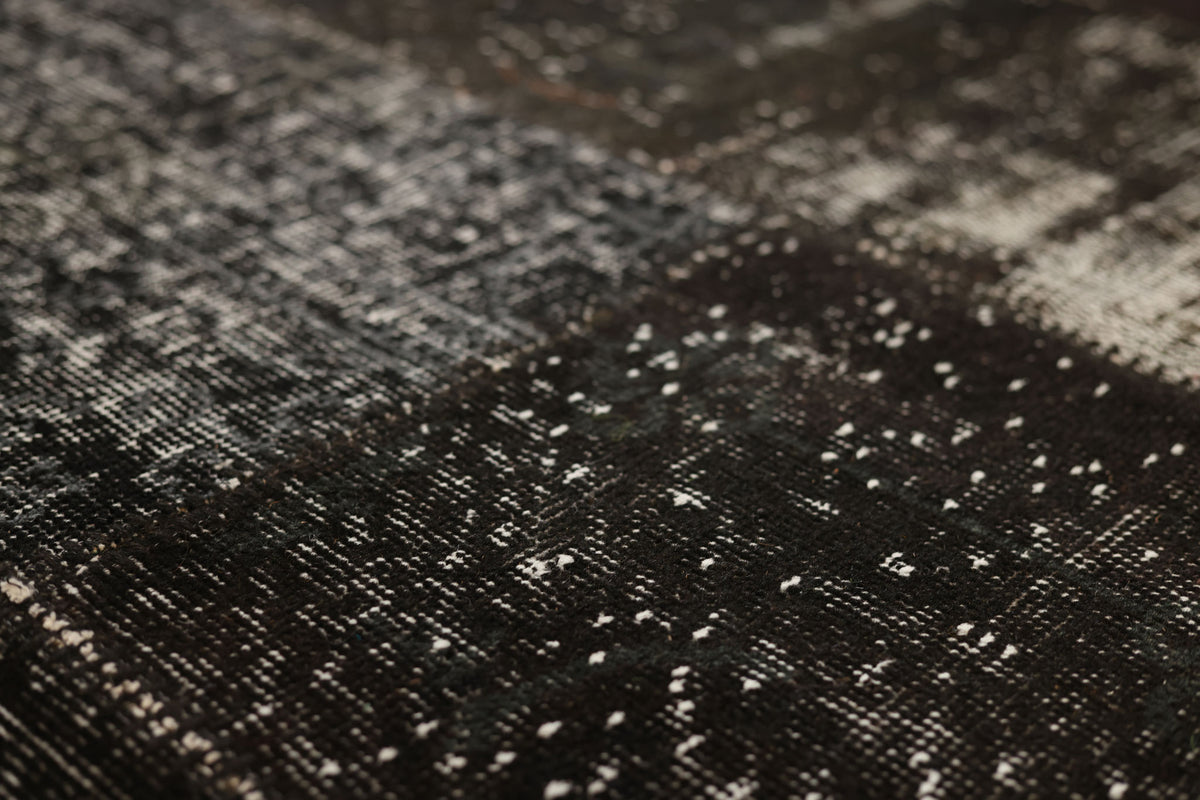 Handmade black patchwork Turkish area rug with distressed, overdyed wool and cotton textures.