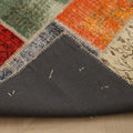 Handmade 5x7 ft vintage Turkish patchwork rug featuring vibrant floral wool and cotton squares with a dark fabric backing.