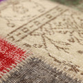 Handmade vintage Turkish patchwork rug featuring wool and cotton floral patterns in vibrant red, purple, and neutral tones.