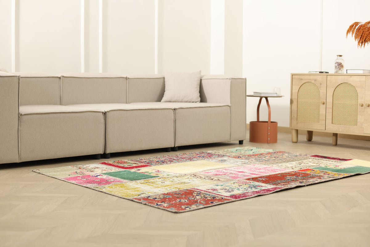 Handmade 5x7 ft vintage Turkish patchwork area rug featuring vibrant floral patterns in wool and cotton in a modern living room.