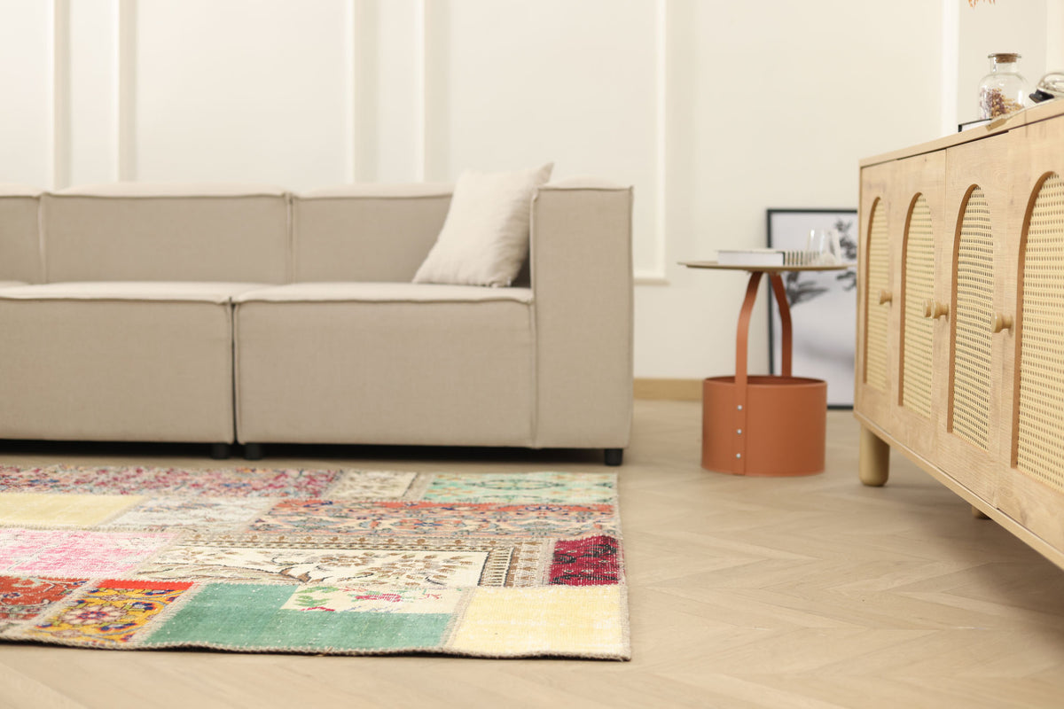 Handmade 5x7 ft vintage Turkish patchwork rug with vibrant floral patterns in wool and cotton on a wooden floor.