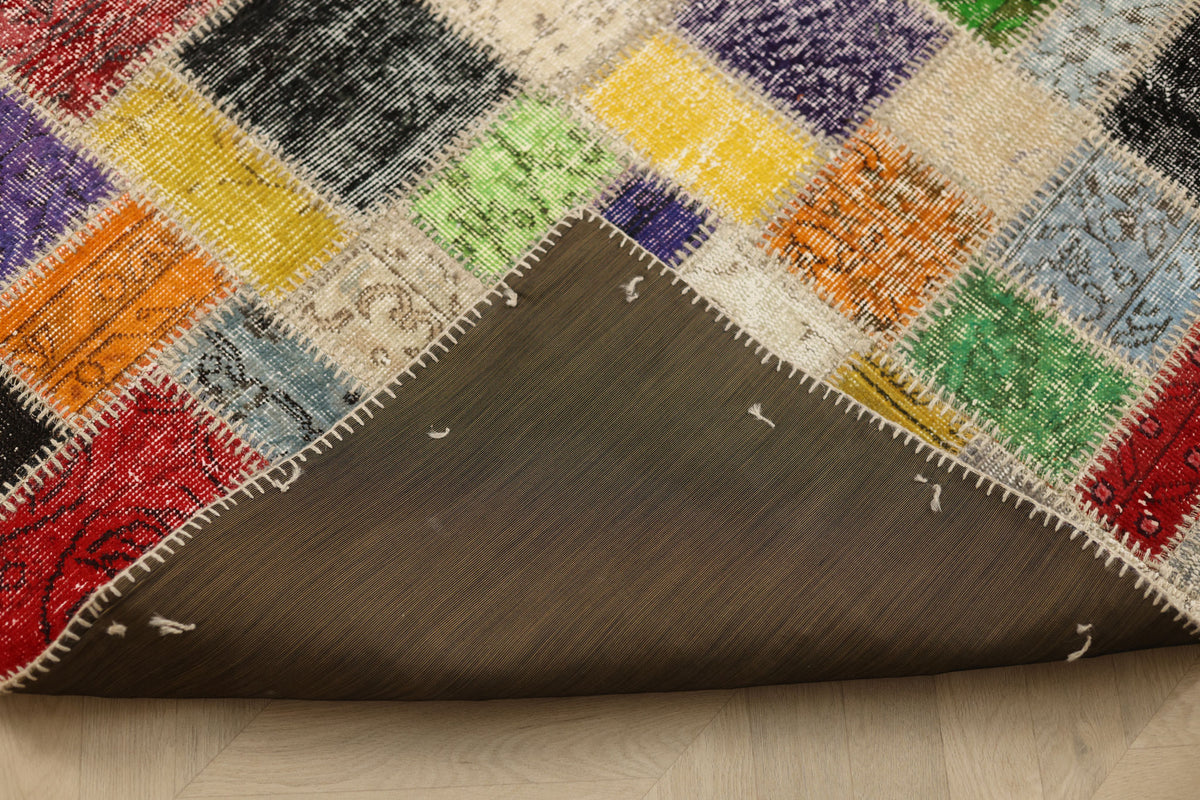 Handmade 6x6 ft patchwork Turkish area rug with vibrant geometric wool and cotton squares and a dark fabric backing.