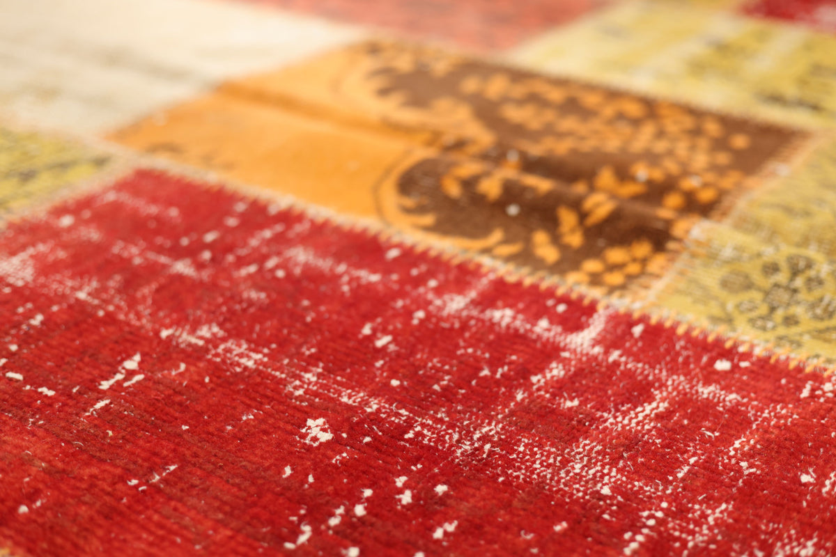 Handmade vintage Turkish patchwork rug in vibrant red and yellow wool with overdyed bohemian patterns.