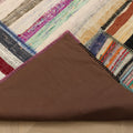 Handmade 6x8 ft vintage Turkish patchwork rug featuring colorful striped wool and cotton patterns with a brown fabric backing.
