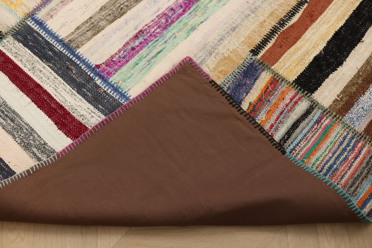 Handmade 6x8 ft vintage Turkish patchwork rug featuring colorful striped wool and cotton patterns with a brown fabric backing.