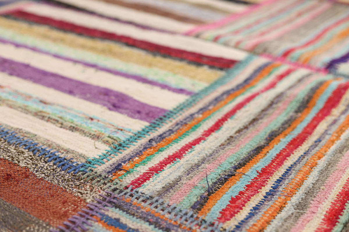 Handmade vintage Turkish patchwork area rug featuring vibrant multicolored stripes and stitched wool and cotton flatweave textures.