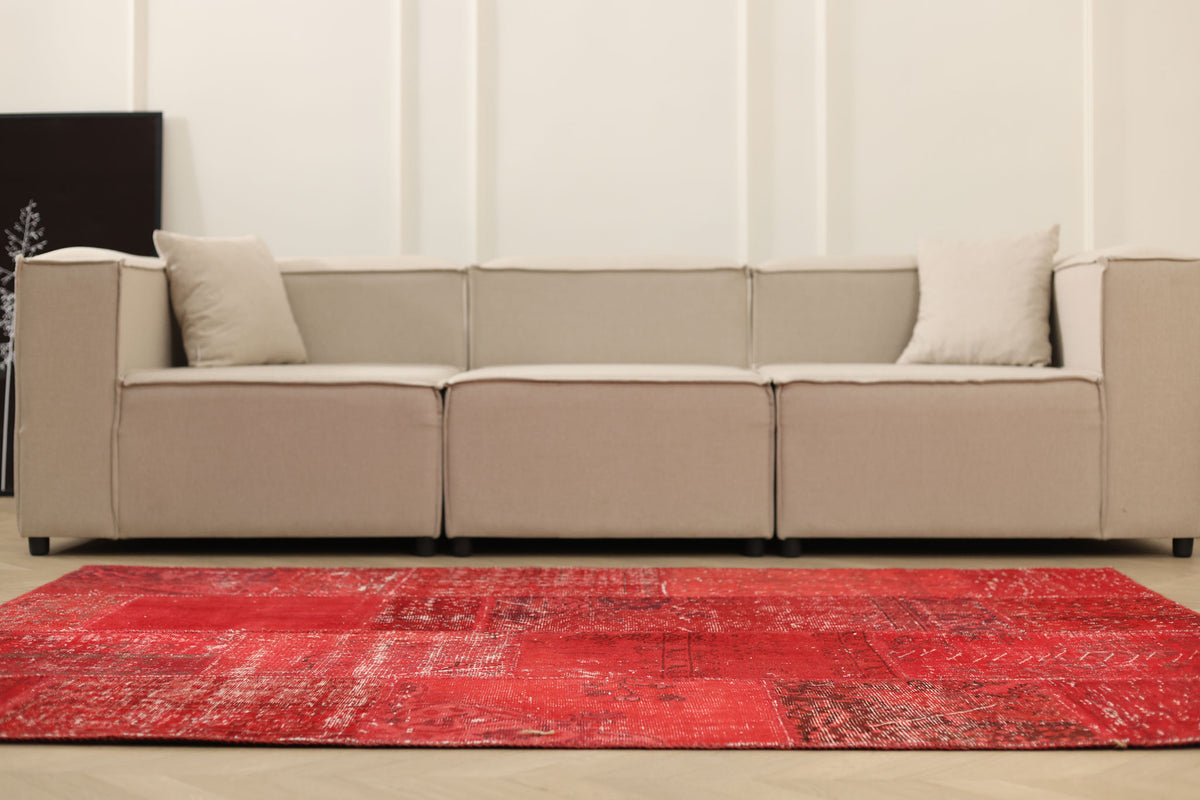 5x7 ft vintage red patchwork Turkish area rug in wool and cotton with overdyed bohemian patterns in a modern living room.