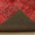 Handmade red patchwork Turkish area rug with a folded corner showing wool and cotton backing and stitched details.
