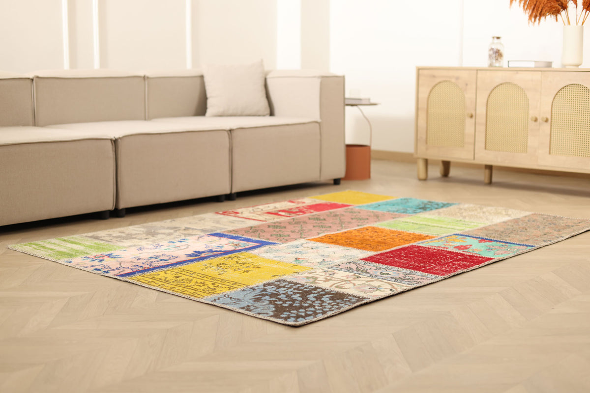 Handmade 5x7 patchwork Turkish area rug featuring vibrant geometric patterns in wool and cotton on a light wood floor.