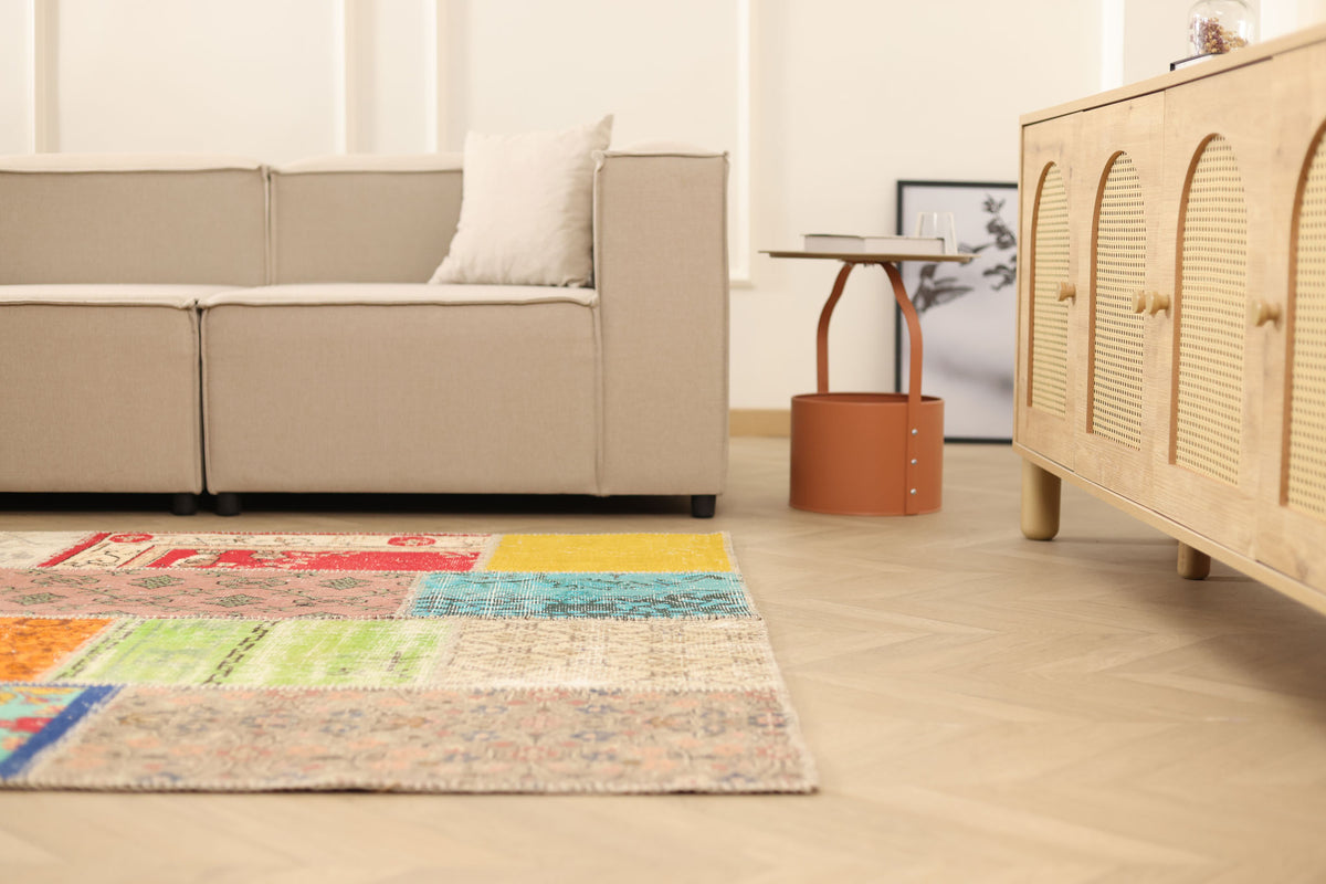 Handmade 5x7 patchwork Turkish area rug featuring vibrant geometric patterns in wool and cotton on a herringbone floor.