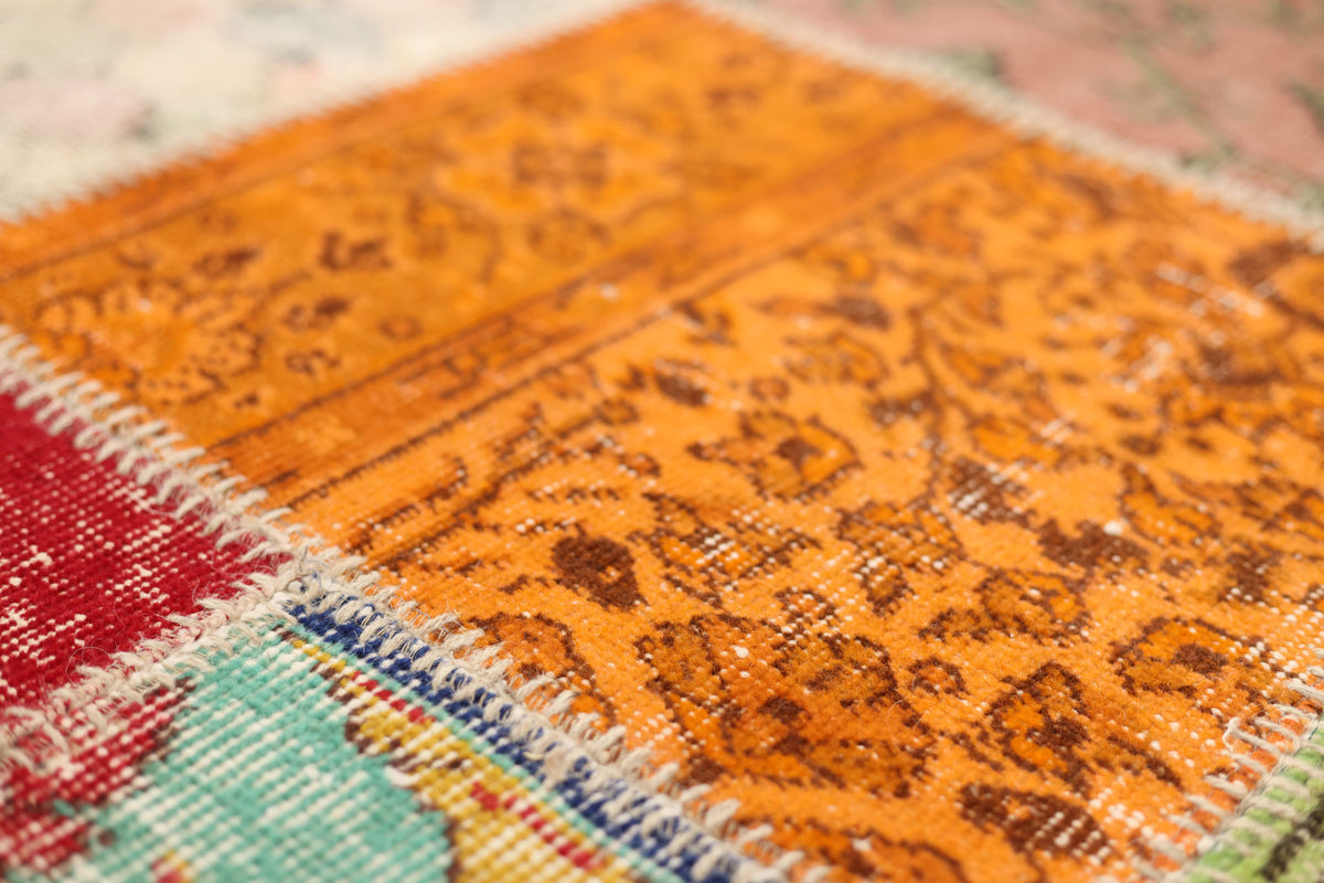 Handmade vintage Turkish patchwork rug with vibrant geometric patterns in wool and cotton, featuring orange and red tones.