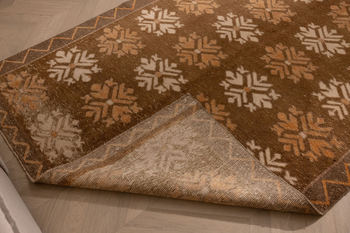 Handwoven brown and beige Turkish runner rug with geometric patterns and a folded corner showing the wool and cotton weave.