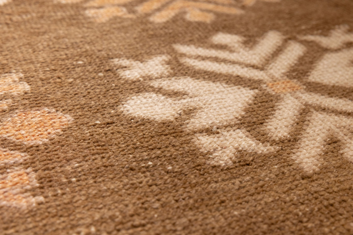 Close-up of a vintage Turkish wool and cotton runner rug featuring brown and beige geometric tribal patterns.