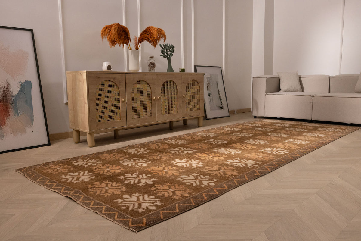 Handwoven 4x12 ft vintage Turkish runner rug in brown and beige with geometric patterns on a light wood floor.