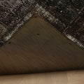 Handmade black patchwork Turkish area rug showing the stitched underside and distressed wool and cotton texture.