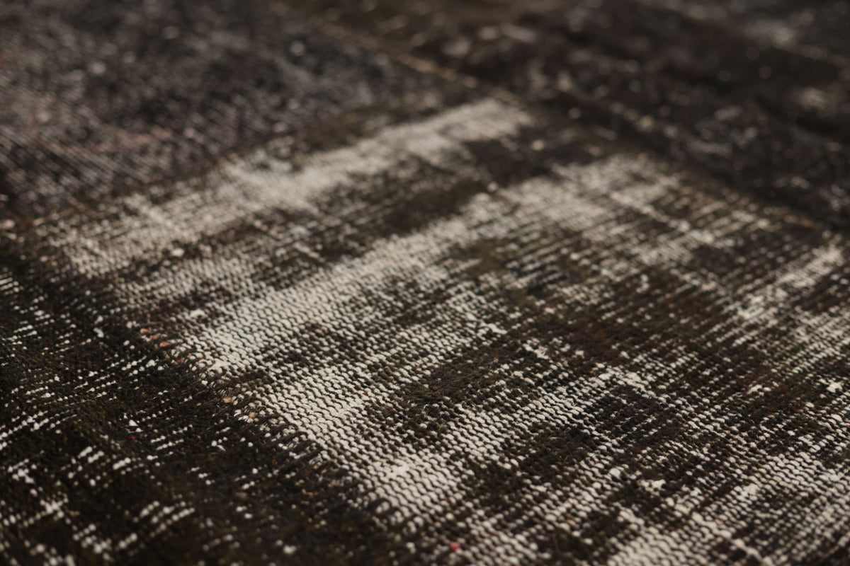 Hand-stitched black patchwork Turkish area rug with a distressed, low-pile wool and cotton texture.