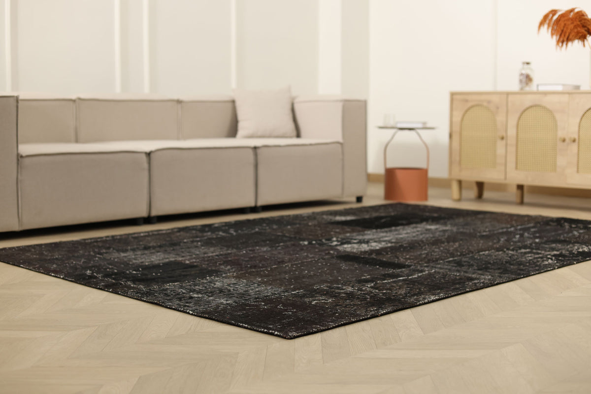 6x9 ft black patchwork Turkish area rug with distressed wool and cotton patterns in a modern bohemian living room.