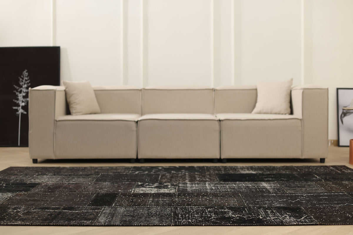 Handmade 6x9 ft black patchwork Turkish area rug with a distressed, vintage-inspired design in wool and cotton.