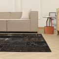 6x9 ft black patchwork vintage Turkish area rug with distressed wool and cotton patterns in a modern living room.