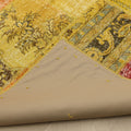 Handmade vintage Turkish patchwork rug in yellow and red with floral patterns, showing the cotton backing and stitching.