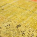Handmade vintage Turkish patchwork rug in yellow and red with floral patterns and a low-pile wool and cotton texture.