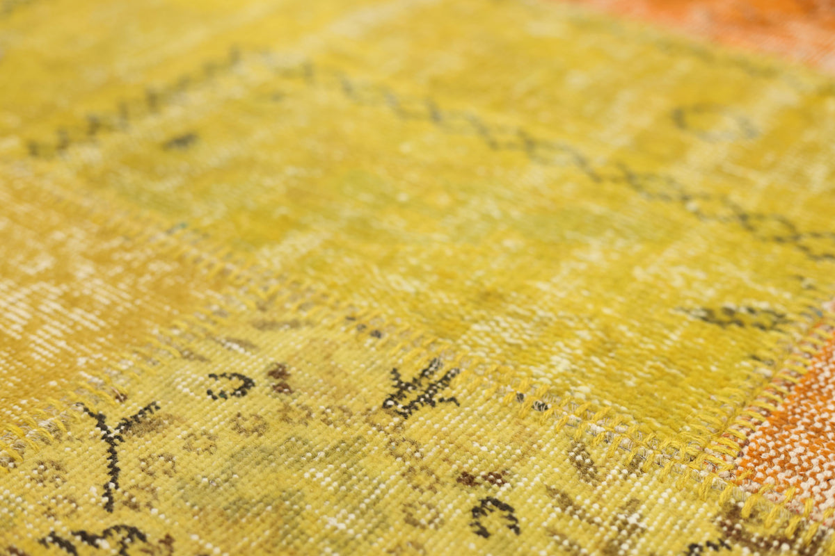 Handmade vintage Turkish patchwork rug in yellow and red with floral patterns and a low-pile wool and cotton texture.